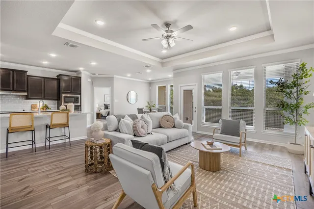 a living room with furniture a rug kitchen view and a large window