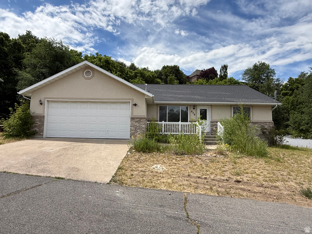 838 East Mountain Road Logan, UT 84321 - Photo 2 of 37 Ranch-style exterior featuring a stucco and stone facade, attached two-car garage, and front porch with white railing