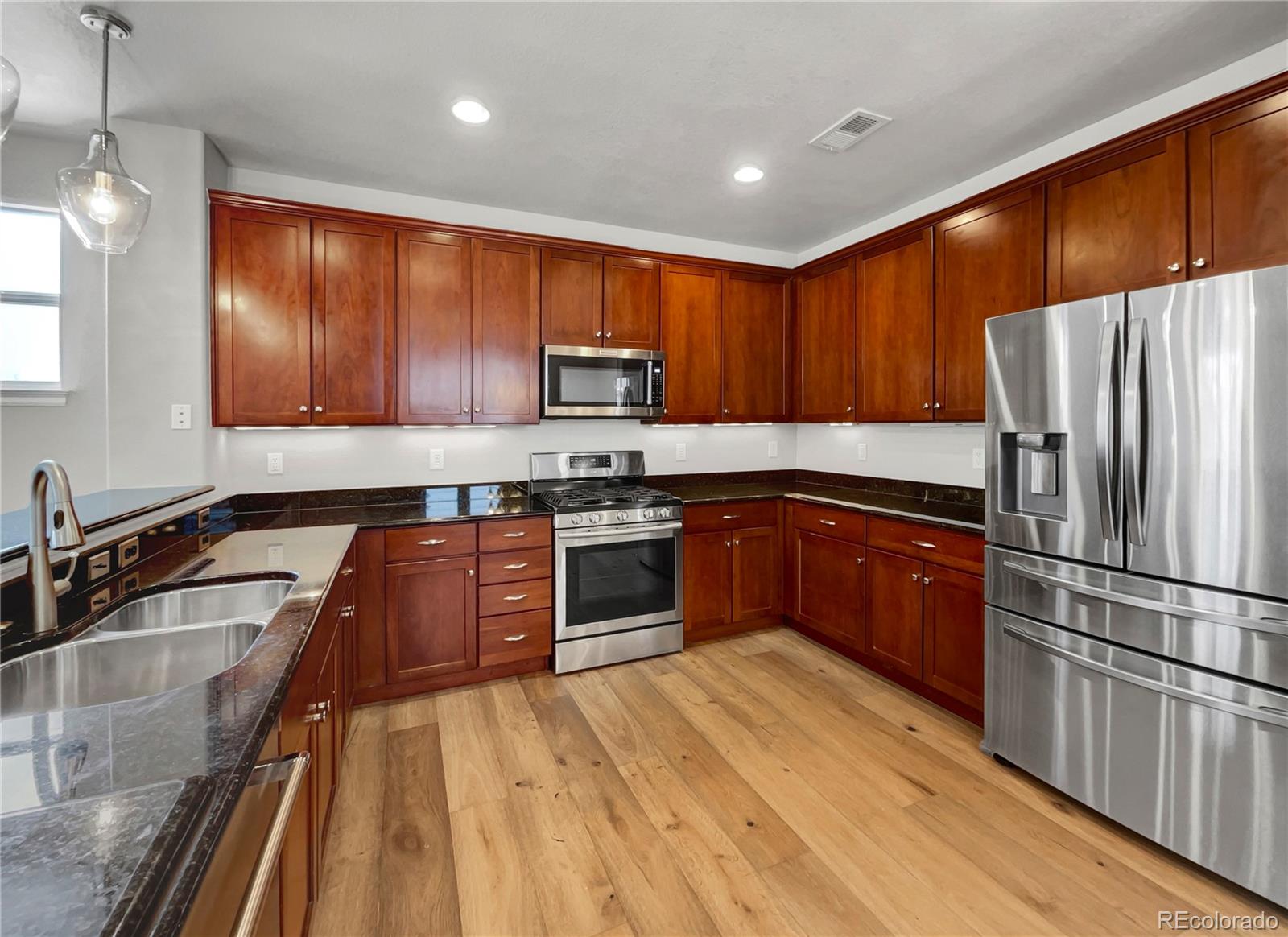 2380 Xanthia Way Denver, CO 80238 - Photo 7 of 19 a kitchen with wooden floors stainless steel appliances and a counter space