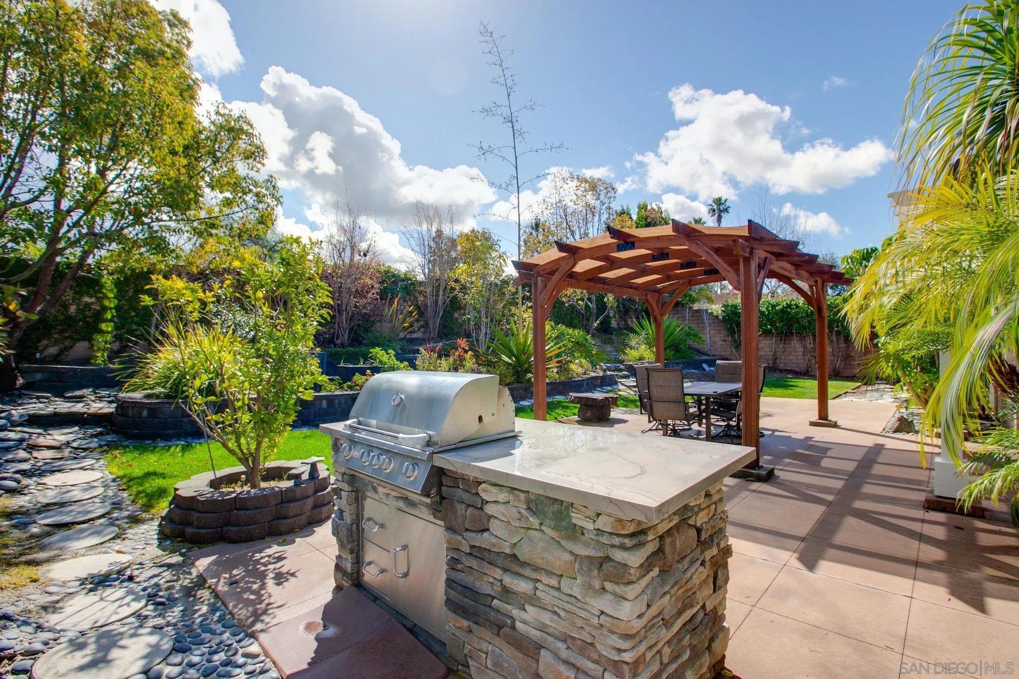1104 Sagewood Drive Oceanside, CA 92056 - Photo 32 of 46 a view of a patio with table and chairs potted plants and a palm tree