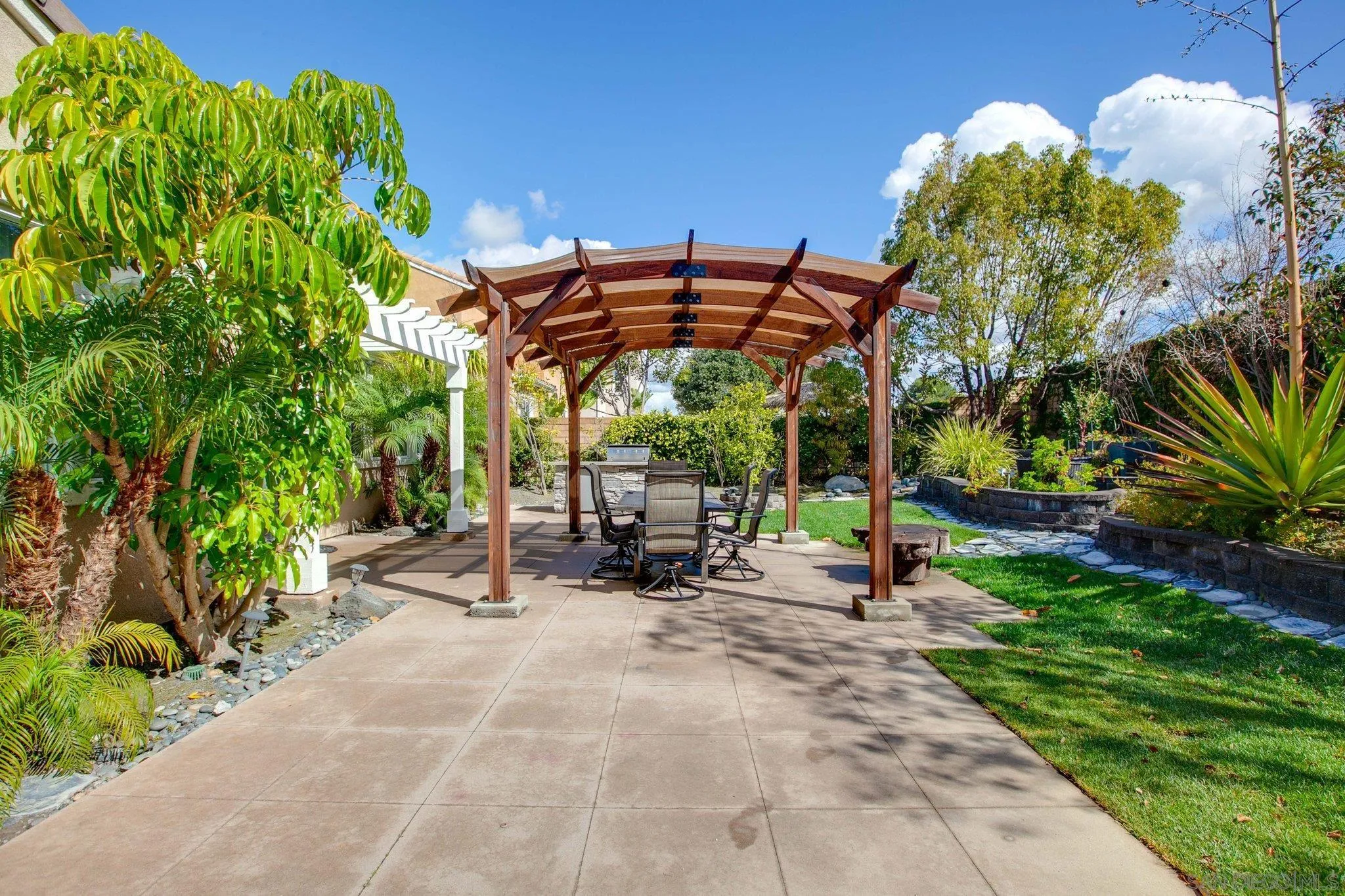 1104 Sagewood Drive Oceanside, CA 92056 - Photo 33 of 46 a view of a patio with table and chairs under an umbrella with potted plants