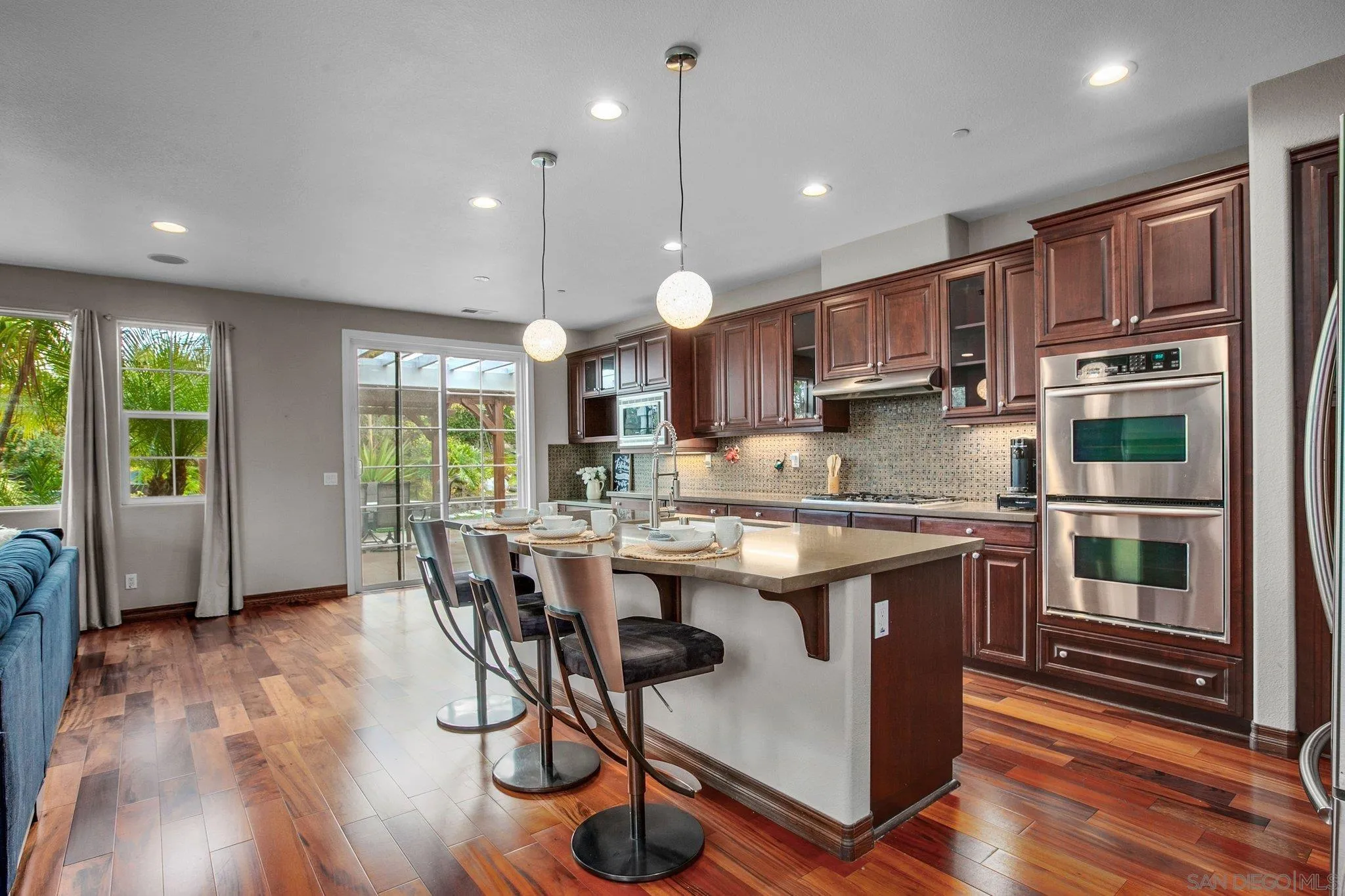 1104 Sagewood Drive Oceanside, CA 92056 - Photo 5 of 46 a kitchen with kitchen island granite countertop wooden floors and wide window