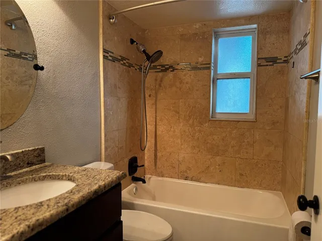 a bathroom with a granite countertop sink toilet and shower