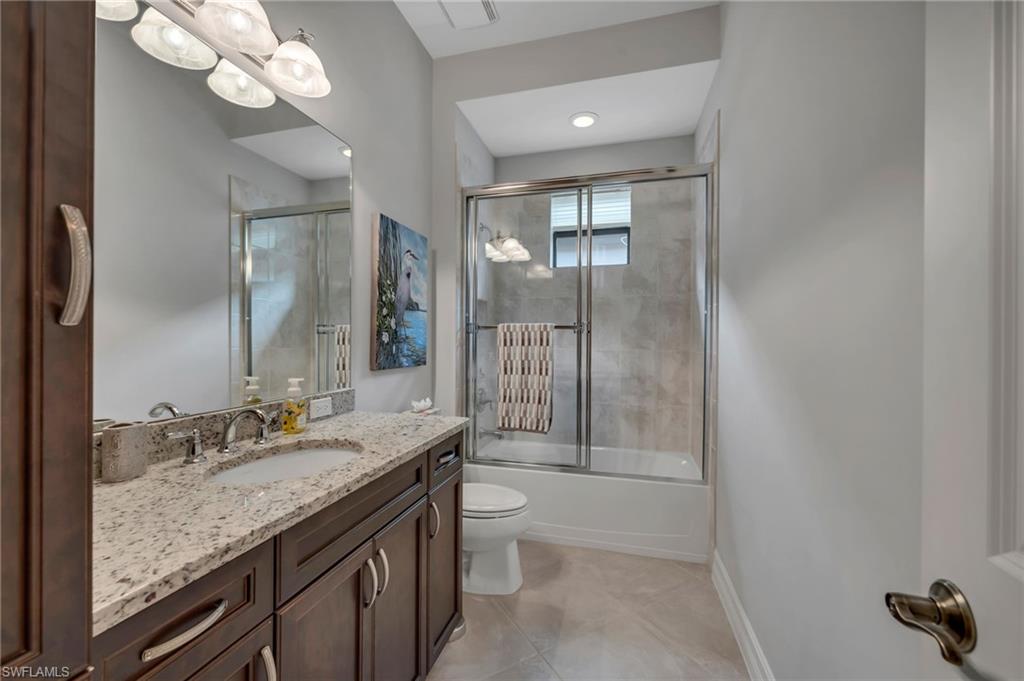 6714 Canwick Cove Circle Naples, FL 34113 - Photo 14 of 23 a bathroom with a granite countertop sink a toilet a mirror and shower