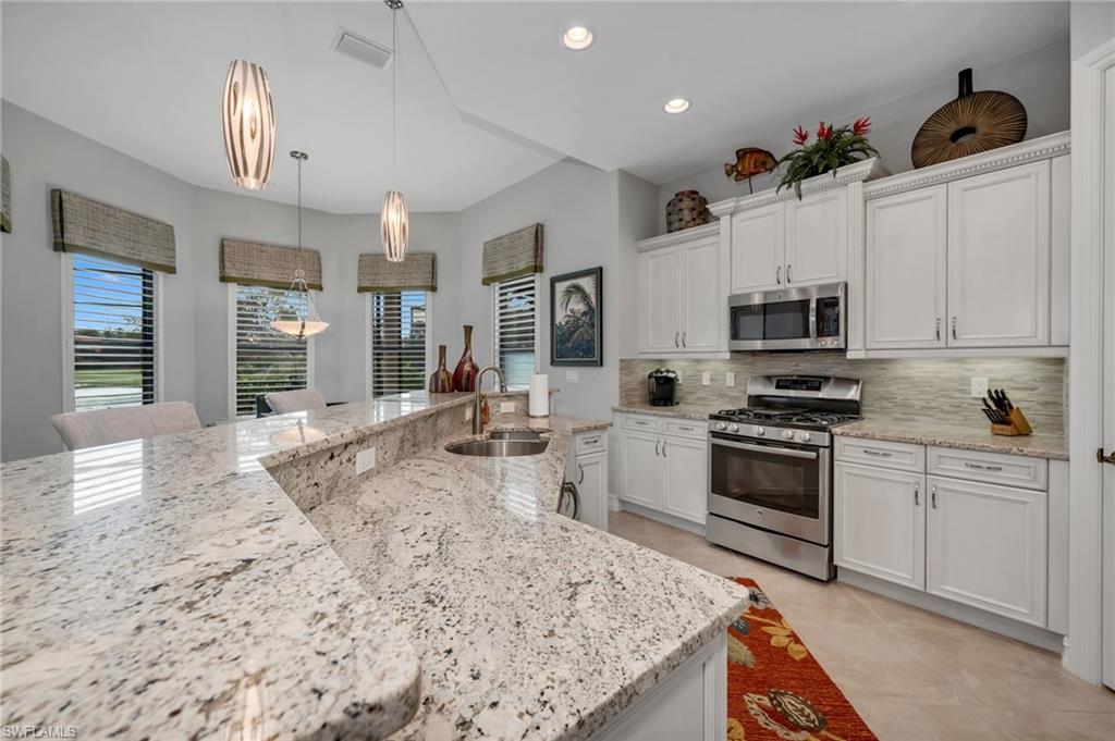 6714 Canwick Cove Circle Naples, FL 34113 - Photo 5 of 23 a kitchen with stainless steel appliances granite countertop a sink stove oven and white cabinets