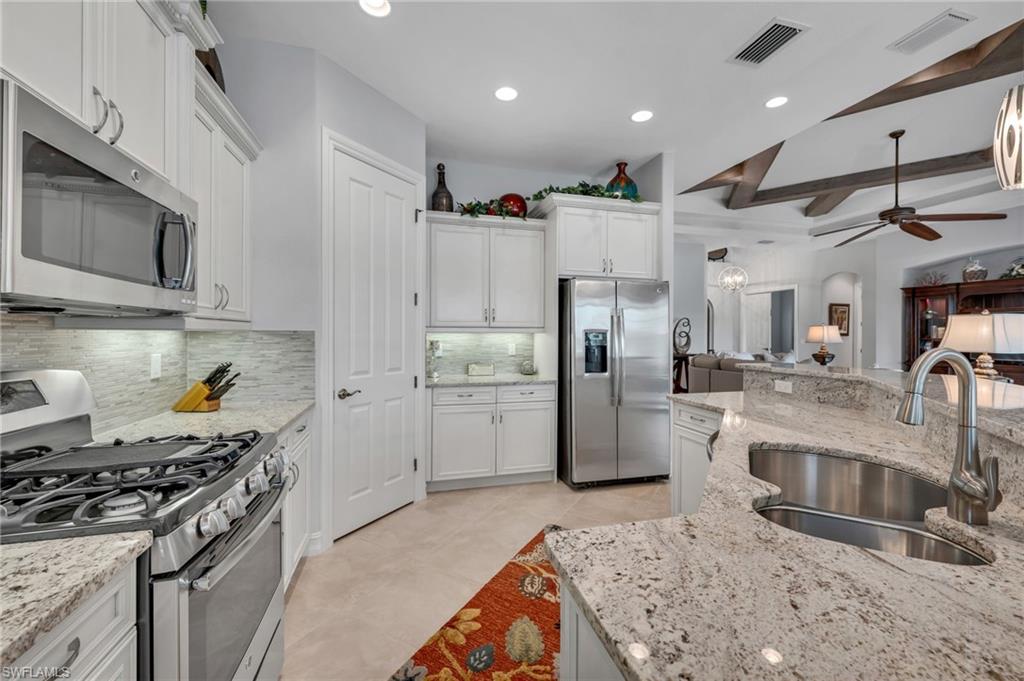 6714 Canwick Cove Circle Naples, FL 34113 - Photo 6 of 23 a kitchen with stainless steel appliances granite countertop a sink stove and refrigerator