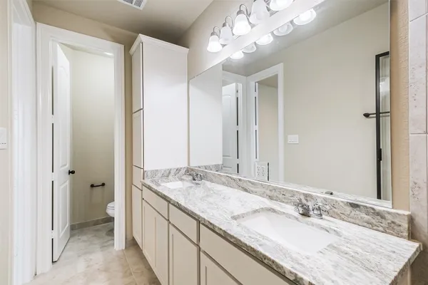 a bathroom with a granite countertop double vanity sink mirror and shower