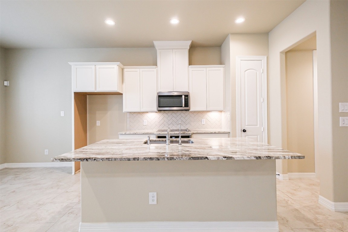11005 Cres Light Way Houston, TX 77043 - Photo 3 of 22 a kitchen with kitchen island granite countertop a stove top oven a sink and white cabinets
