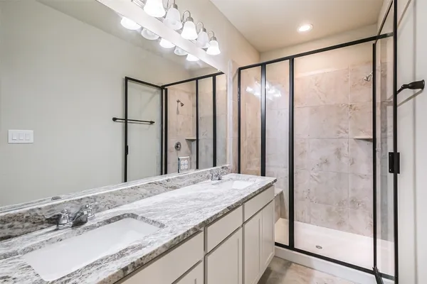 a bathroom with a granite countertop sink a mirror and shower