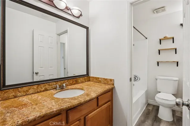 a bathroom with a granite countertop sink and a toilet