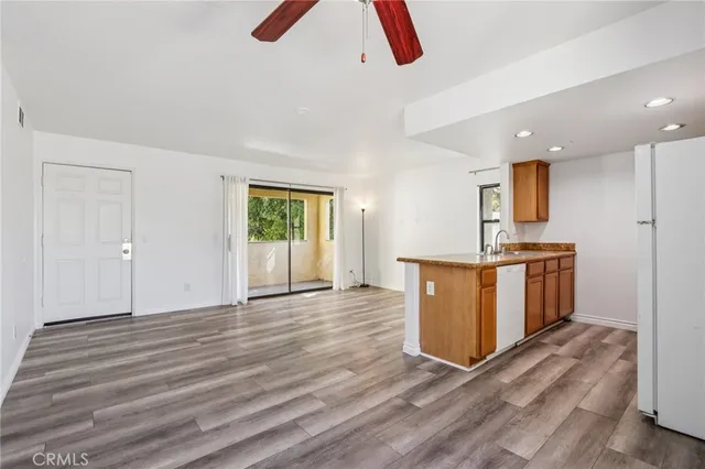 a view of kitchen and empty room with wooden floor