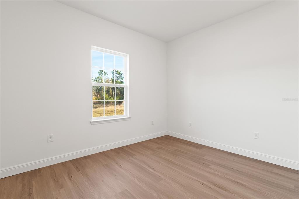 6790 Southwest 129th Street Ocala, FL 34473 - Photo 22 of 23 an empty room with wooden floor and a window