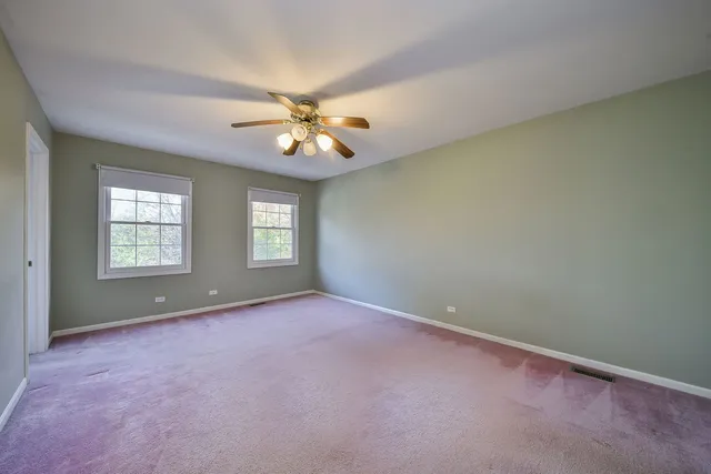 an empty room with windows and chandelier fan