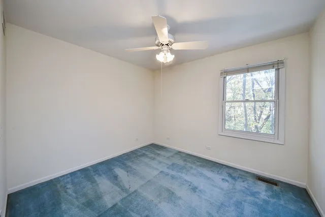 an empty room with a window and a fan