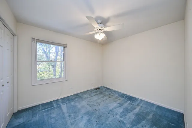 an empty room with a window and ceiling fan