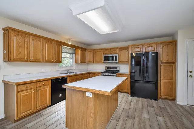 a kitchen with stainless steel appliances granite countertop a refrigerator a sink dishwasher a stove with wooden cabinets and floor