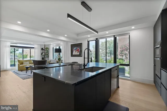 a dining hall with stainless steel appliances granite countertop a sink a counter and chairs