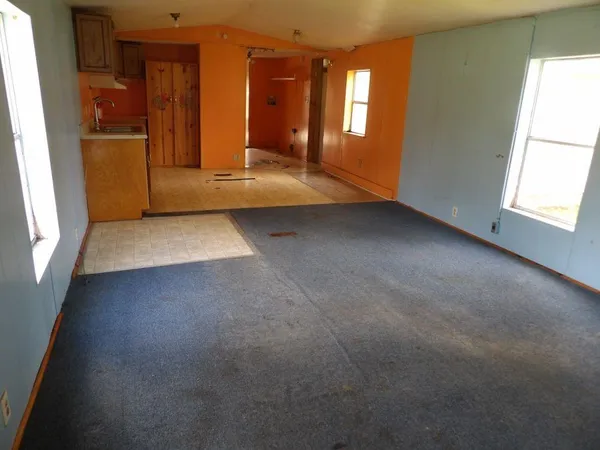 a view of an empty room with window and a kitchen