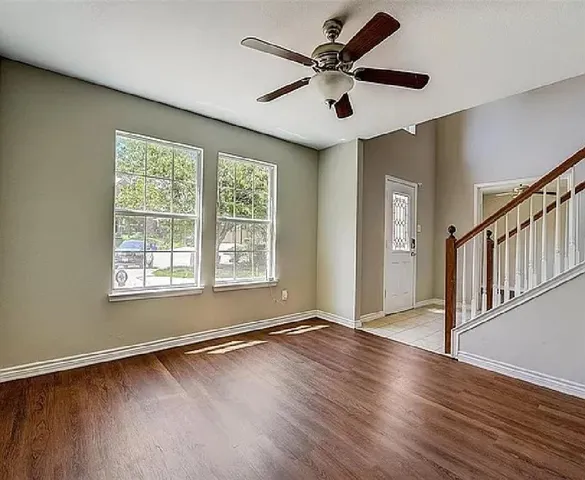 a view of an empty room with wooden floor and a window