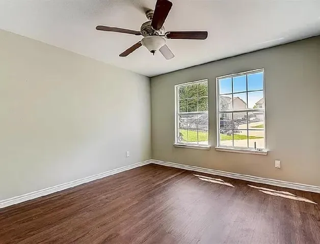 a view of an empty room with a window and wooden floor