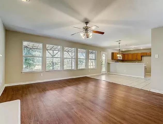 a view of an empty room with window and wooden floor