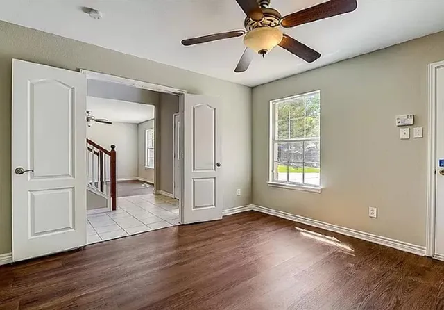 a view of empty room with wooden floor and fan