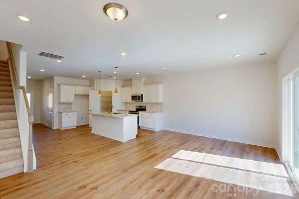 a view of kitchen with kitchen island a sink wooden floor and a refrigerator