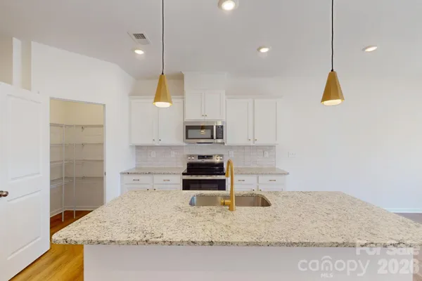 a kitchen with kitchen island a counter top space appliances and cabinets