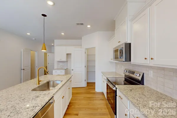 a kitchen with granite countertop a sink a counter top space stainless steel appliances and cabinets