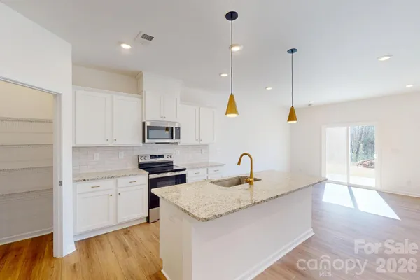 a kitchen with stainless steel appliances granite countertop a sink a stove and a wooden floors