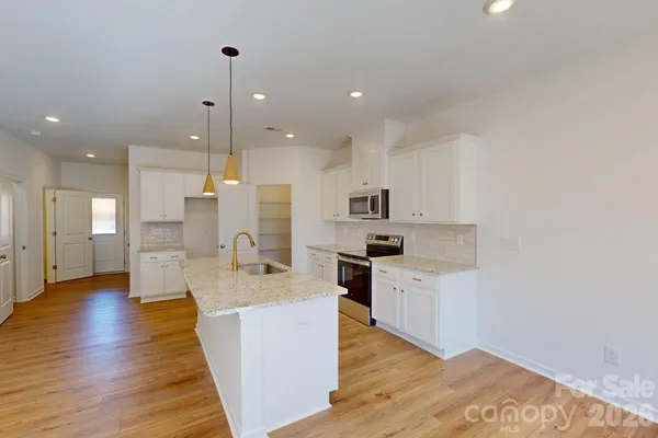 a large kitchen with stainless steel appliances kitchen island a large counter top and a wooden floors