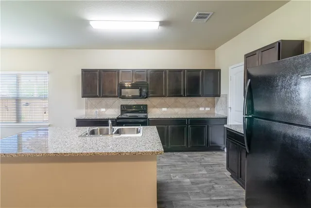 a kitchen with kitchen island granite countertop a stove sink and refrigerator