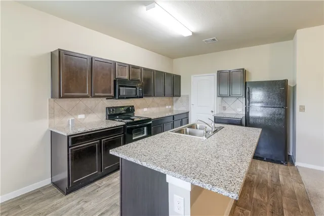 a kitchen with kitchen island granite countertop stainless steel appliances and wooden cabinets