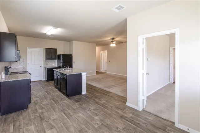 a large kitchen with a center island and wooden floor