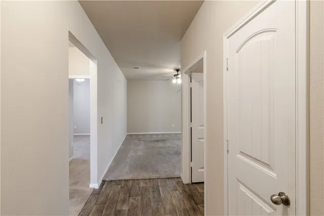 a view of a hallway with wooden floor and a bathroom