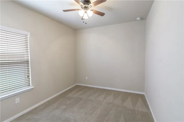 an empty room with a window and a fan