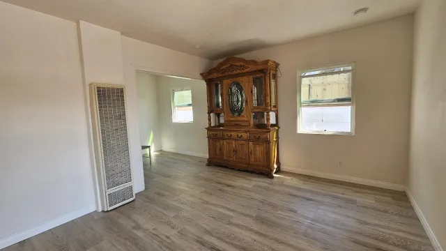 an empty room with wooden floor cabinet and windows