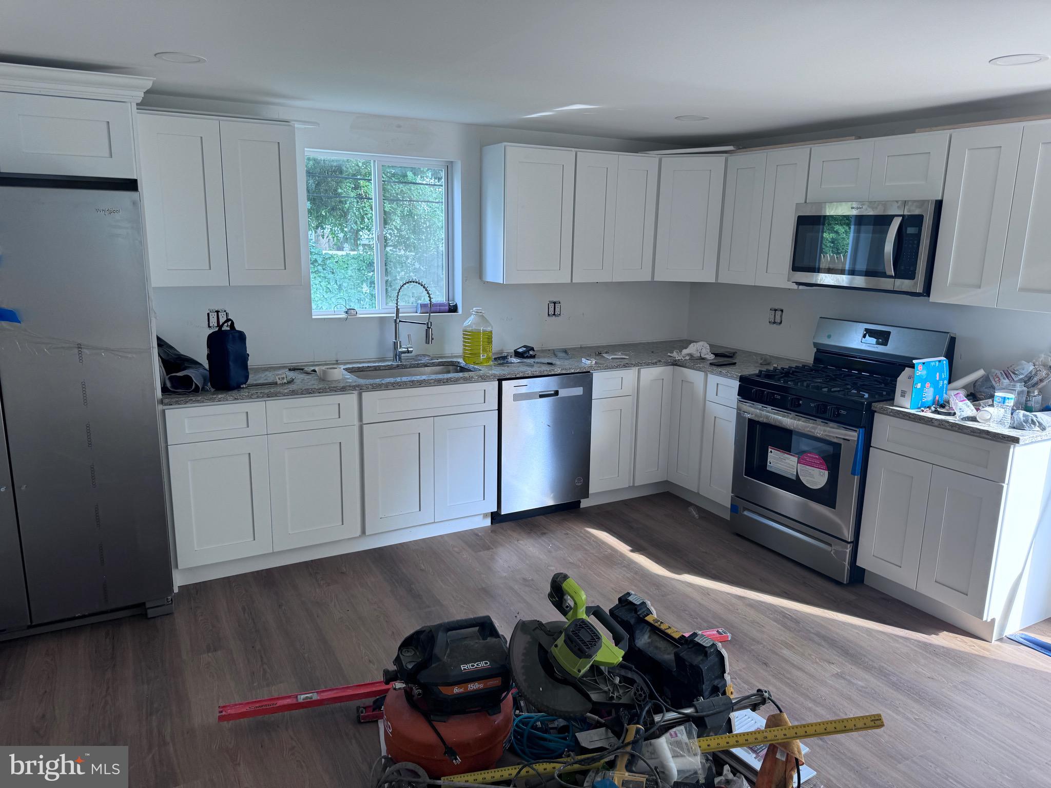 4667 Hawthorne Street Philadelphia, PA 19124 - Photo 19 of 21 a kitchen with stainless steel appliances kitchen island granite countertop a stove a sink dishwasher and a microwave with wooden floor