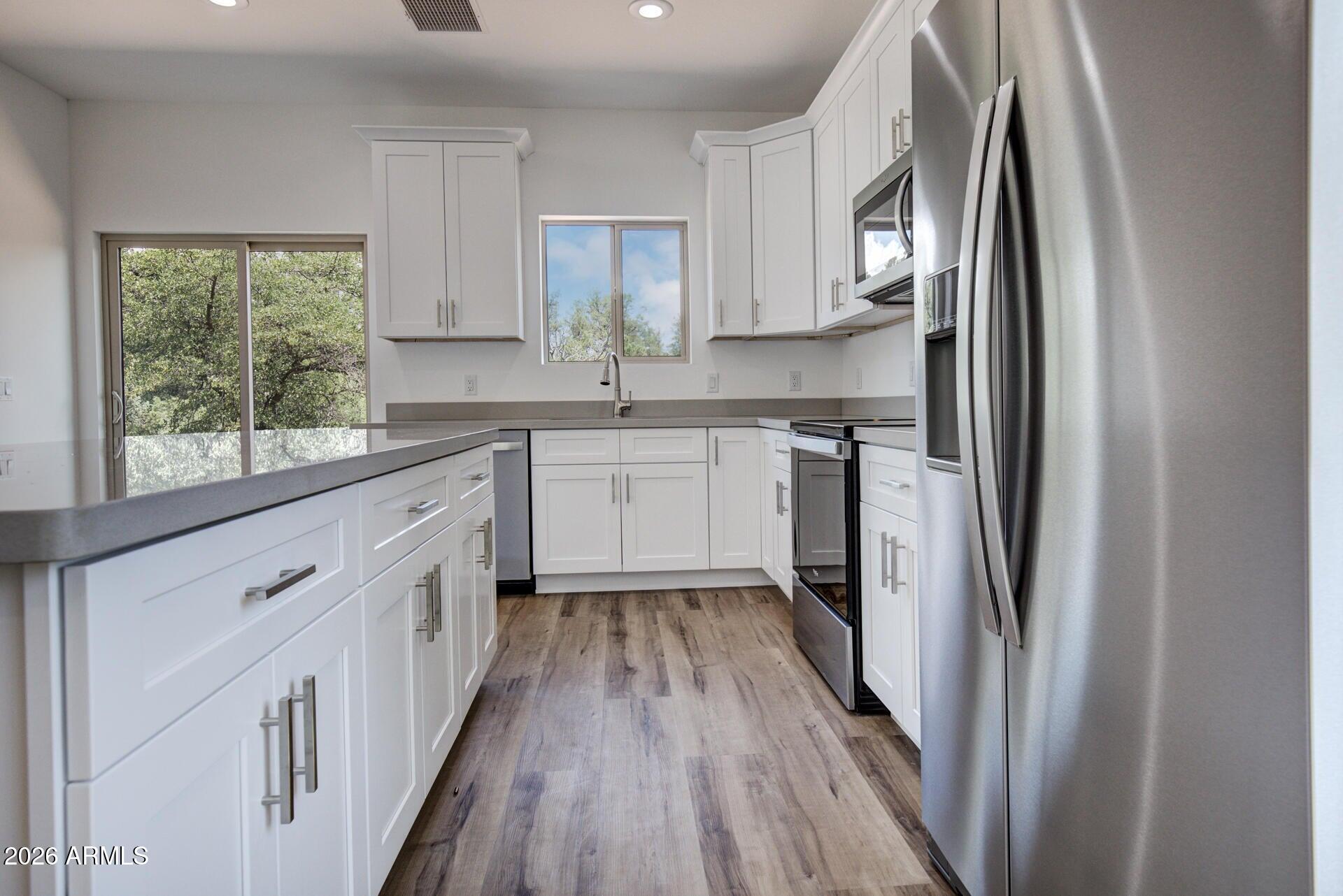 2002 East Thunder Mountain Payson, AZ 85541 - Photo 10 of 34 a kitchen with stainless steel appliances granite countertop a refrigerator a sink dishwasher a stove and white countertops with wooden floor