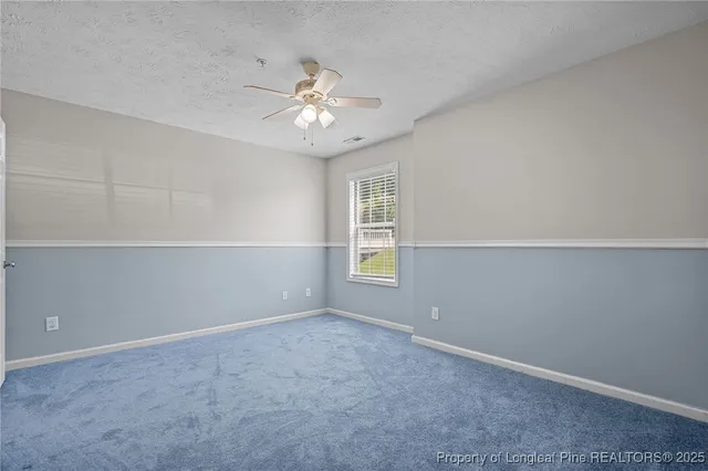 a view of an empty room with chandelier fan