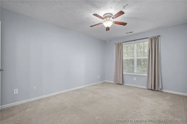 a view of an empty room with a chandelier fan