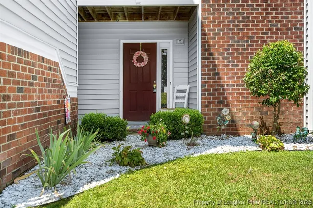 a view of a brick house with a yard and plants