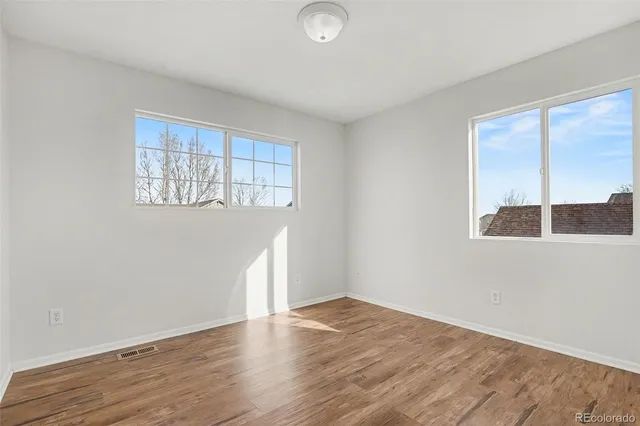 an empty room with wooden floor and windows