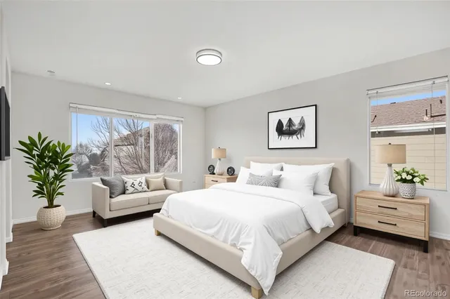 a bedroom with a large bed couch and windows