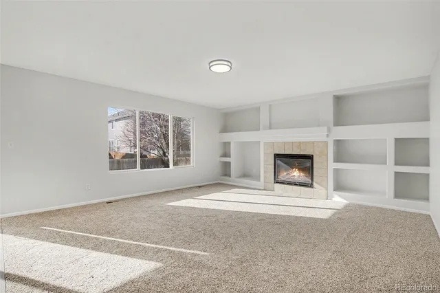 a view of an empty room with a fireplace and a window