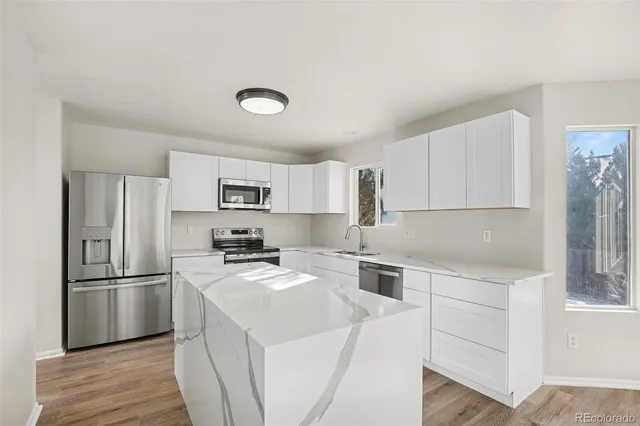 a kitchen with a refrigerator a stove top oven a sink and cabinets