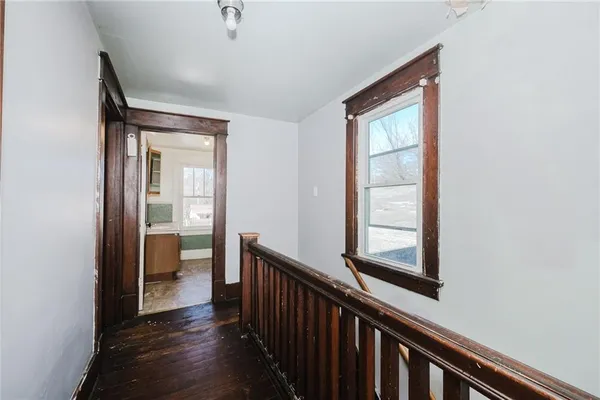a view of a hallway with wooden floor and a bathroom