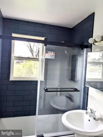 a bathroom with a sink a bathtub and next to a window