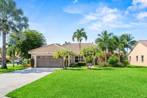 a view of a house with a yard and palm trees
