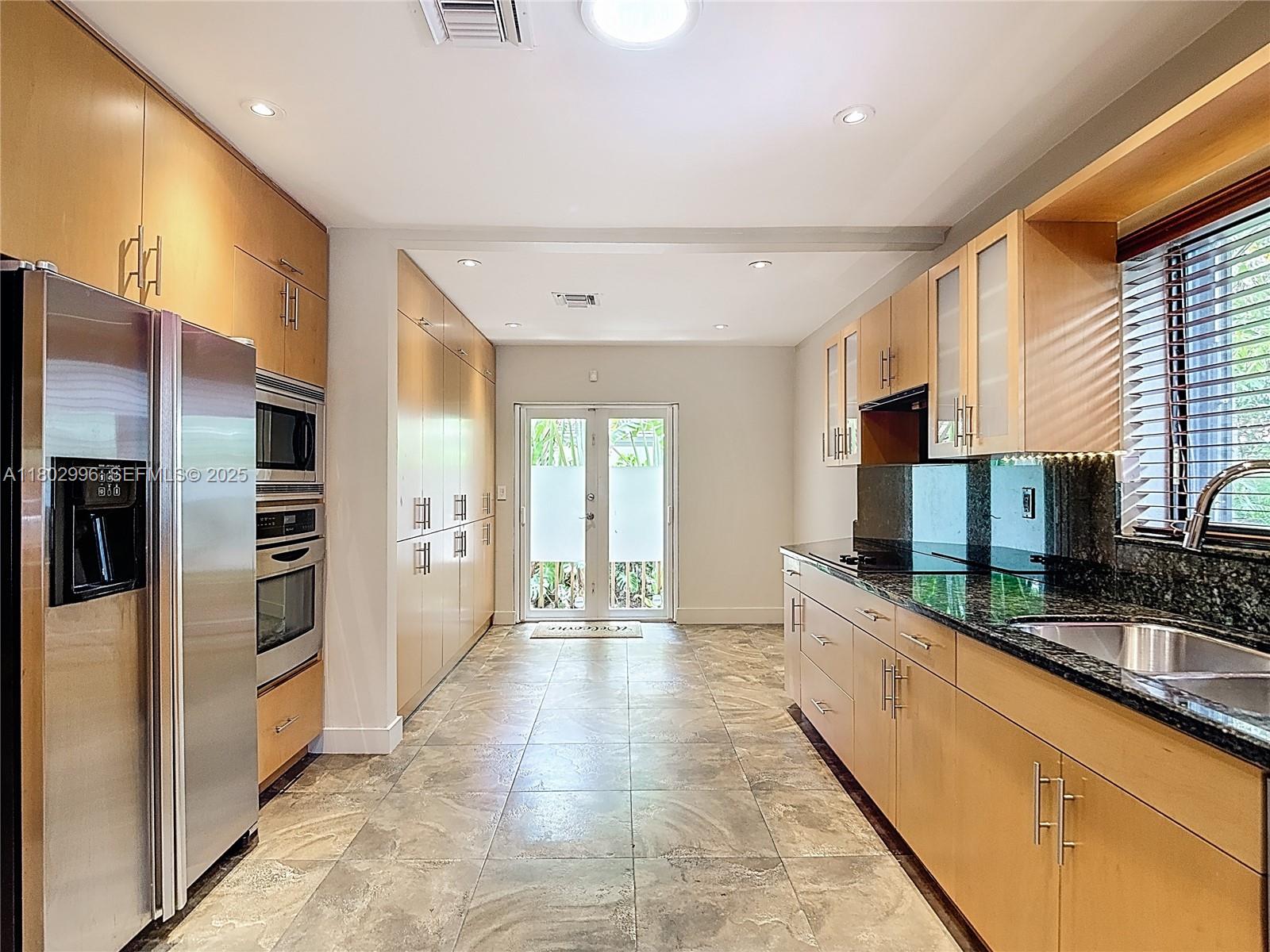 2810 Crystal Court Miami, FL 33133 - Photo 5 of 14 a large kitchen with stainless steel appliances kitchen island granite countertop a refrigerator and a sink